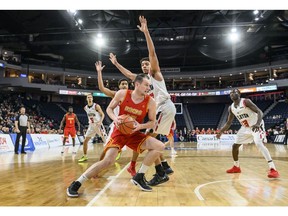 University of Calgary Dinos' Brett Layton, centre, tries to drive around Carleton Ravens' Eddie Ekiyor during the first half of the gold medal final in the USports men's basketball national championship in Halifax on Sunday, March 10, 2019.