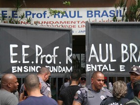 Police officers guard the entrance of the Raul Brasil State School in Suzano, Brazil, Wednesday, March 13, 2019.