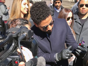 Empire actor Jussie Smollett appears with a fan as he walks out of the Leighton Criminal Court Building after a hearing Tuesday, March 26, 2019, in Chicago. Smollett attorneys Tina Glandian and Patricia Brown Holmes said in a statement Tuesday that Smollett's record "has been wiped clean." Smollett was indicted on 16 felony counts related to making a false report that he was attacked by two men who shouted racial and homophobic slurs.