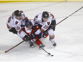 Calgary Hitmen L-R, Josh Prokop and Carson Focht battle Lethbridge Hurricanes, Calen Addison in third period WHL Play-Off action at the Scotiabank Saddledome in Calgary on Thursday, March 28, 2019. Darren Makowichuk/Postmedia