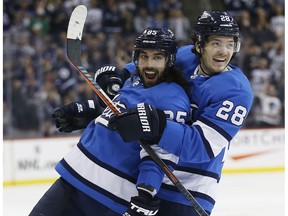 Winnipeg Jets' Mathieu Perreault (85) and Jack Roslovic (28) celebrate Perreault's go ahead goal on Calgary Flames goaltender Mike Smith (41) during second period NHL action in Winnipeg on Saturday, March 16, 2019.