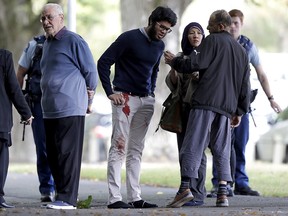 People stand across the road from a mosque in central Christchurch, New Zealand, Friday, March 15, 2019. At least 49 people have died mass shootings at two mosques.