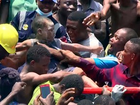 In this image taken from video, people help a child after he was rescued from the scene of a building collapse in Lagos, Nigeria, Wednesday March 13, 2019.