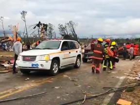 People walk amid debris in Lee County, Ala., after what appeared to be a tornado struck in the area Sunday, March 3, 2019.