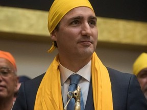 Prime Minister Justin Trudeau stands after having a scarf placed on him and being presented with a gift after speaking at the Khalsa Diwan Society Sikh Temple before marching in the Vaisakhi parade, in Vancouver on Saturday April 13, 2019 (The Canadian Press)