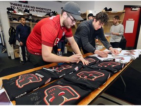 Calgary Hitmen Luke Coleman, left and Dakota Krebs sign jerseys during the team's locker cleanout day at the Scotiabank Saddledome on Thursday. Photo by Gavin Young/Postmedia.