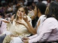 Chrissy Teigen, left, reacts after Heat star Dwyane Wade (not pictured) crashed into her causing her to spill her drink on her husband, John Legend, during NBA action at American Airlines Arena in Miami on Tuesday, April 9, 2019.