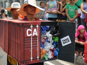 Filipino environmental activists wear a mock container vans filled with garbage to symbolize the 50 containers of waste that were shipped from Canada to the Philippines two years ago, as they hold a protest outside the Canadian embassy at the financial district of Makati, south of Manila, Philippines on May 7, 2015.