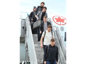 Calgary Flames players walk off the plane after arriving in Calgary from Colorado on Thursday. Photo by Jim Wells/Postmedia.