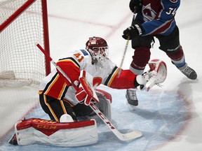 Calgary Flames goaltender Mike Smith, front, makes a glove save on a shot by Colorado Avalanche center Carl Soderberg during the first period of Game 4 of an NHL hockey playoff series Wednesday, April 17, 2019, in Denver. (AP Photo/David Zalubowski) ORG XMIT: CODZ119