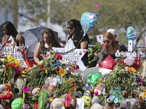 In this Feb. 25, 2018 file photo, mourners bring flowers as they pay tribute at a memorial for the victims of the shooting at Marjory Stoneman Douglas High School, in Parkland, Fla.