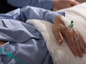 A close-up of a terminally ill man's hand with drip.
