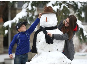 Brother and sister Talon Knapfl, 10, and  Kayla Readshaw, 15, work on a snowman on the front lawn of their northwest Highwood neighbourhood home on Sunday. Photo by Jim Wells/Postmedia.