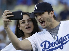 In this Oct. 19, 2016, file photo, Ashton Kutcher and wife Mila Kunis take a selfie before Game 4 of the National League baseball championship series between the Chicago Cubs and the Los Angeles Dodgers in Los Angeles.