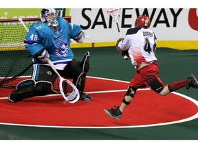 Calgary Roughnecks Dane Dobbie charges in to make a shot against Rochester Knighthawks Matt Vinc  in NLL action at the Scotiabank Saddledome in Calgary, Alberta, on May 24, 2014. The Roughnecks beat the Knighthawks 10-7. Mike Drew/Calgary Sun/QMI AGENCY
