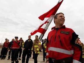 High Level firefighters welcome residents home with a giant Canada flag on their return to High Level after being evacuated due to the Chuckegg Creek wildfire on Monday, June 3, 2019.