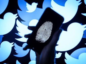 In this photo illustration, a thumbprint is displayed on a mobile phone as the logo for the Twitter social media network is projected onto a screen on August 09, 2017 in London, England.