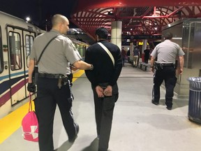 Transit safety officers lead a suspect away from the Erlton/Stampede CTrain station on June 23, 2017.