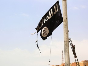 In this file photo taken on April 30, 2017, a member of the U.S.-backed Syrian Democratic Forces removes an Islamic State flag in the town of Tabqa. (DELIL SOULEIMAN/AFP/Getty Images)