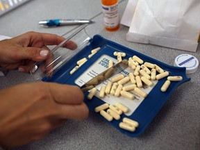 A pharmacist counts out antibiotic pills in this file photo. An expert panel is recommending that Canada adopt a single-payer pharmacare plan.