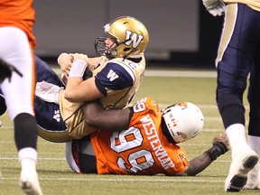 Winnipeg Blue Bombers’ quarterback Brian Brohm #12 (top) get sacked by BC Lions’ Jabar Westerman #99 during the second half of a CFL game against the BC Lions in Vancouver, B.C. on Saturday September 13, 2014. Carmine Marinelli/QMI Agency
