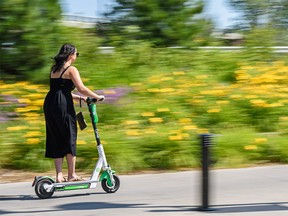 A Lime e-scooter rider commutes on Riverwalk in East Village on Monday, July 29, 2019. Azin Ghaffari/Postmedia Calgary