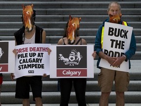 PETA supporters wearing horse masks protest in front of the Alberta Legislature on Tuesday, July 16, 2019.