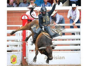 Sage Steele Kimzey of Strong City, Okla., hangs on tight for an 91 on a bull named Nickle Package during the bull-riding event at the Calgary Stampede rodeo on Friday. Photo by Al Charest/Postmedia.