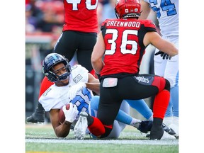 Calgary Stampeders LB Cory Greenwood knocks Rodney Smith of the Toronto Argonauts to the turf during CFL football in Calgary on Thursday. Photo by Al Charest/Postmedia.
