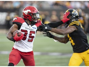 CP-Web.  Calgary Stampeders running back Ka'Deem Carey (35) gets a hand into the face of Hamilton Tiger Cats defensive back Richard Leonard (4) during first half CFL football game action in Hamilton, Ont., on Saturday, July 13, 2019.