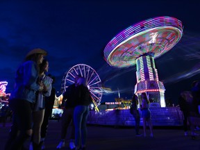 Hannah Riggins, left, stands with a friend as they watch the rides at the Calgary Stampede midway, Sunday evening, July 7, 2019.
