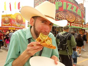 Postmedia reporter Sammy Hudes tries a "Pickle Pizza" on the midway at the Calgary Stampede on Wednesday, July 10, 2019. Brendan Miller/Postmedia
