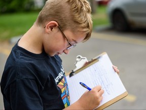 Isaac, 10, signs a petition against the closing of Inglewood Public Pool on Sunday, August 25, 2019. The Inglewood community association hosted a pool party to gather support from the members of the community against the closure of Inglewood Public Pool.   Azin Ghaffari/Postmedia Calgary