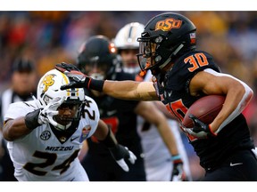 MEMPHIS, TENNESSEE - DECEMBER 31: Chuba Hubbard #30 of the Oklahoma State Cowboys runs with the ball as Terez Hall #24 of the Missouri Tigers defends during the first half of the AutoZone Liberty Bowl at Liberty Bowl Memorial Stadium on December 31, 2018 in Memphis, Tennessee.