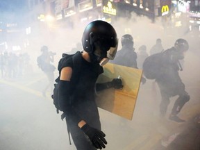 Demonstrators are seen amidst smoke from tear gas during an anti-extradition bill protest in Hong Kong on Sunday, Aug. 4, 2019.