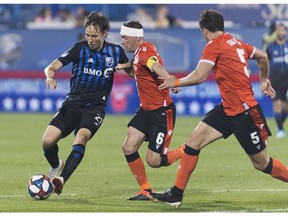 CP-Web.  Montreal Impact's Lassi Lappalainen, left, is challenged by Cavalry Fc's Nikolas Ledgerwood (6) and Mason Trafford (5) during second halfsemi-final Canadian Championship soccer action in Montreal, Wednesday, August 7, 2019.