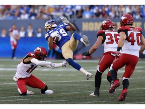Winnipeg Blue Bombers receiver Kenny Lawler (centre) is spun around by Calgary Stampeders defensive back Royce Metchie (left) during CFL action in Winnipeg on Thurs., Aug. 8, 2019. Kevin King/Winnipeg Sun/Postmedia Network