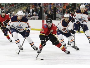 Matthew Phillips of the Calgary Flames enters the offensive zone while pursued by Edmonton Oilers' Raphael Lavoie and Steven Iacobellis during the Young Guns Battle of Alberta game Saturday, Sept. 7, 2019 at the Westerner Park Centrium in Red Deer.