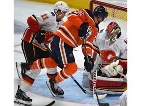 Edmonton Oilers Colby Cave (12) pursed by Calgary Flames Mikael Backlund (11) as he screens goalie Jon Gillies (32) during pre-season NHL action at Rogers Place in Edmonton, September 20, 2019. Ed Kaiser/Postmedia