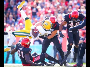 Edmonton Eskimos Natey Adjei is tackled by Cordarro Law and Cory Greenwood with the Calgary Stampeders during CFL football in Calgary on Monday, September 2, 2019. Al Charest/Postmedia