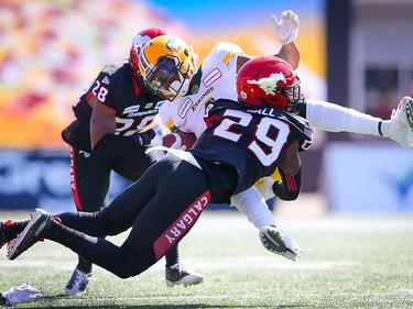 Edmonton Eskimos Tevaun Smith is tackled by Brandon Smith and Jamar Wall of the Stampeders in Calgary on Monday, September 2, 2019. Al Charest/Postmedia