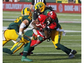 Sep 7, 2019; Edmonton, Alberta, Canada; Calgary Stampeders running back KaÕDeem Carey (35) is brought down by Edmonton Eskimos defensive back Don Unamba (0) and defensive back Josh Johnson (26) during a Canadian Football League game at Commonwealth Stadium. Mandatory Credit: Perry Nelson-USA TODAY Sports ORG XMIT: USATSI-408206