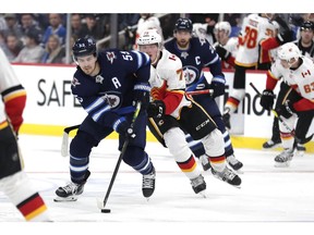 Sep 22, 2019; Winnipeg, Manitoba, CAN;  Calgary Flames right wing Eetu Tuulola (75) chases down Winnipeg Jets center Mark Scheifele (55) in the second period at Bell MTS Place. Mandatory Credit: James Carey Lauder-USA TODAY Sports ORG XMIT: USATSI-406660