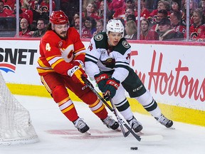 Rasmus Andersson of the Calgary Flames battles for the puck against Joel Eriksson Ek of the Minnesota Wild during an NHL game at Scotiabank Saddledome on March 2, 2019 in Calgary.