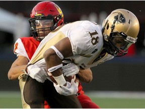 Dinos DB Deane Leonard tackles Bisions Receiver Macho Bockru during second-half action as the U of C Dinos beat the University of Manitoba Bisons 24-10 at McMahon Stadium on Friday night. Photo by Brendan Miller/Postmedia.