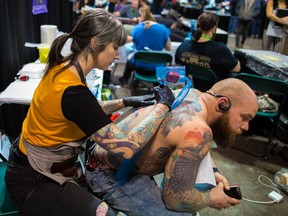 Tattoo artist Alicia Simms works on client Marcus Murphy during the Calgary Tattoo and Arts Festival at the BMO Centre on Oct. 14, 2018. The annual event returns this weekend.