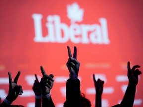 Liberal Party supporters flash victory signs while watching the live federal election results in Montreal on Oct. 21, 2019.