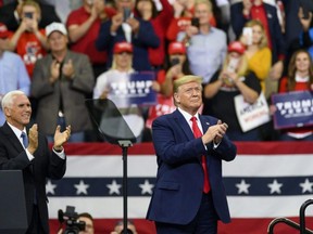 U.S. Vice President Mike Pence (left) claps as President Donald Trump takes the stage during a campaign rally at the Target Center in Minneapolis, on Thursday, Oct. 10, 2019.