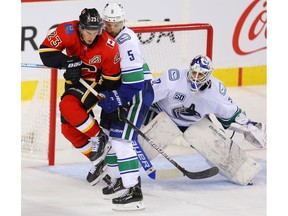 Calgary Flames Sean Monahan battles Oscar Fantenberg for the puck in front of goalie Richard Bachman of the Vancouver Canucks during pre-season NHL hockey in Calgary on Monday September 16, 2019. Al Charest / Postmedia