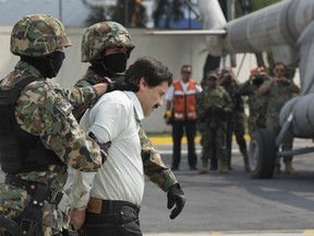 Drug trafficker Joaquin 'El Chapo' Guzman is escorted to a helicopter by Mexican security forces at Mexico's International Airport in Mexico city, Mexico, on Saturday, Feb. 22, 2014.